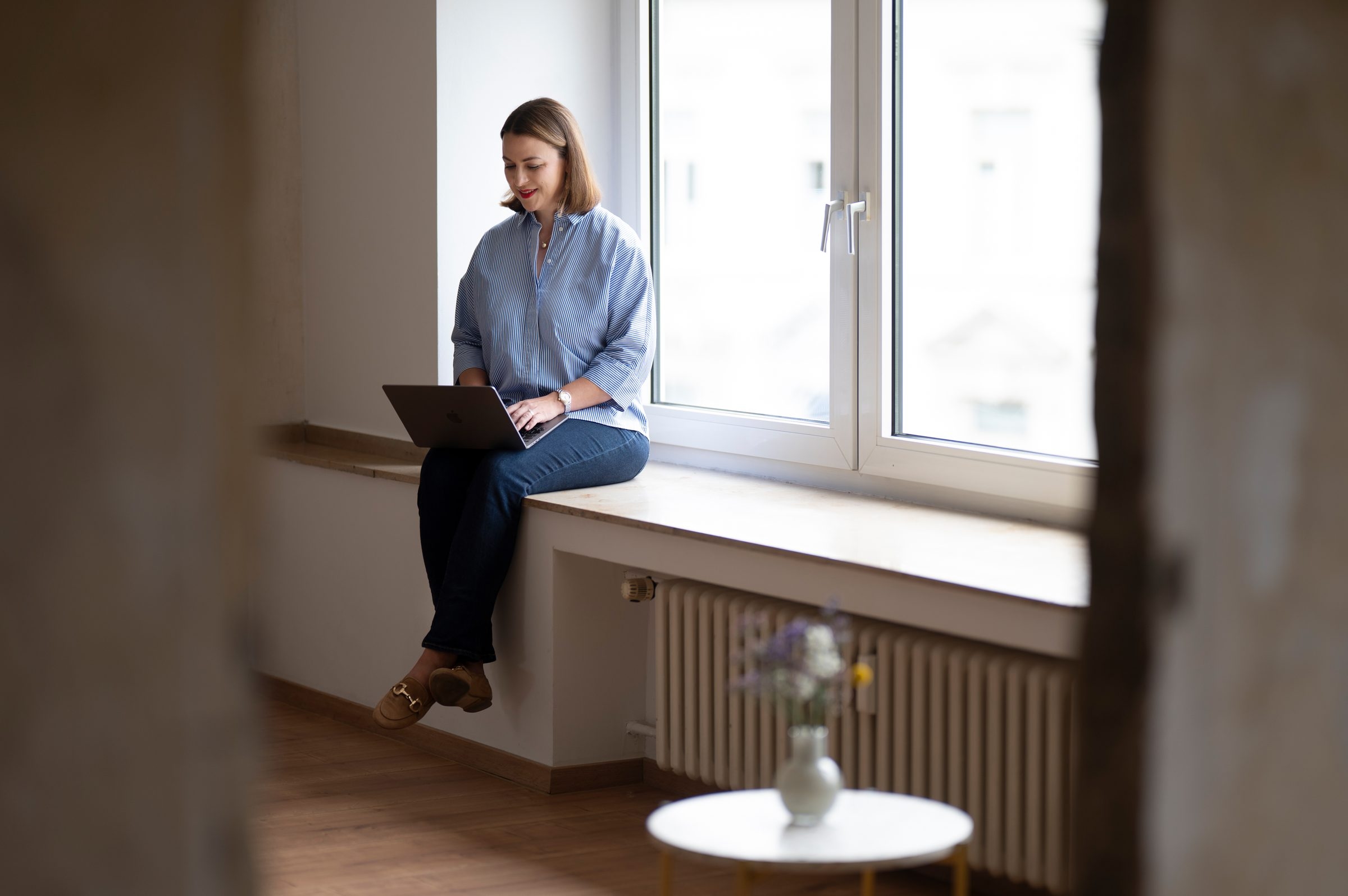 Victoria Beckers von Energie durch Entwicklung telefoniert und hält eine Kaffeetasse in der Hand – Momentaufnahme durch eine Glasscheibe, die Fokus und Ruhe vermittelt.