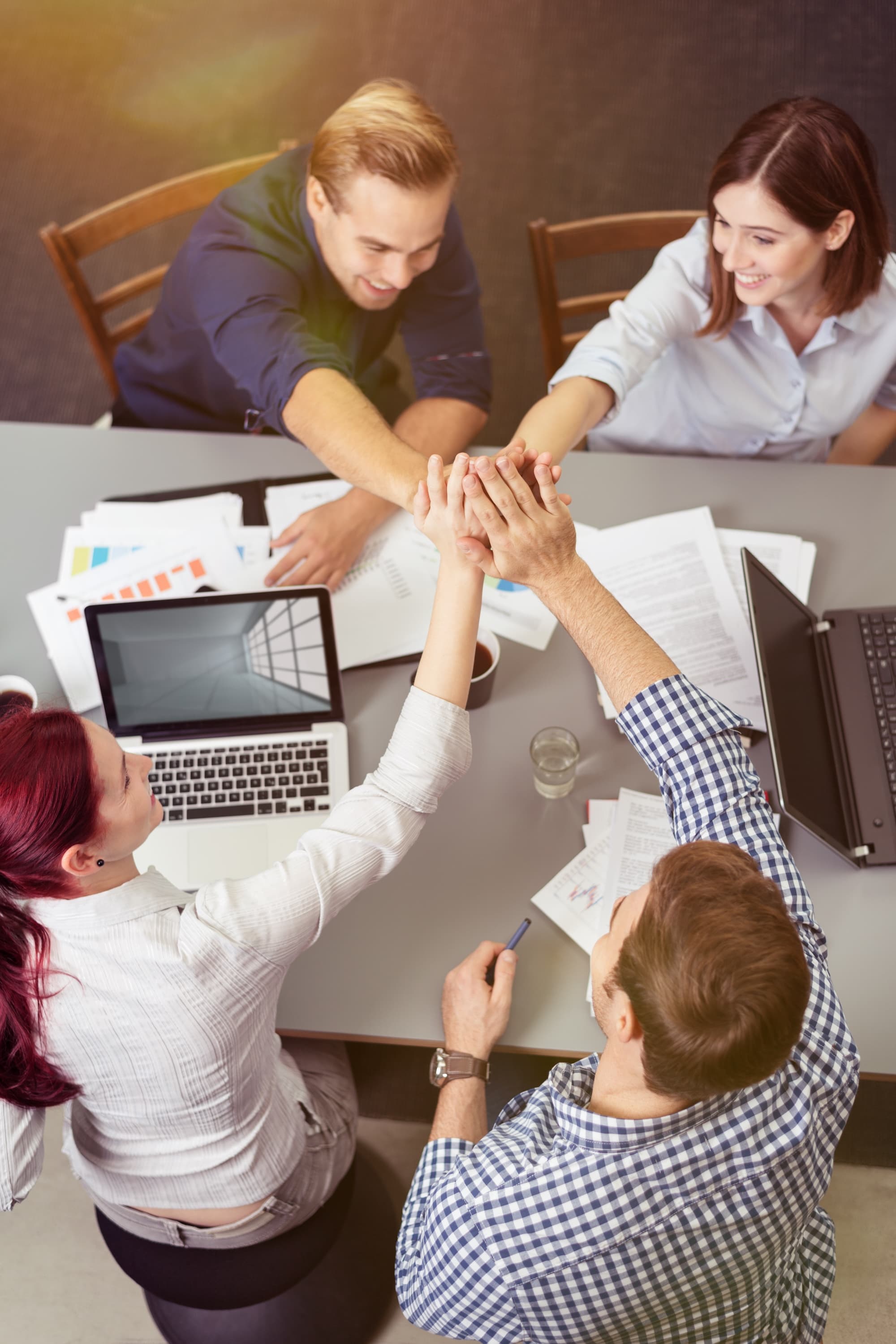 Young people in an office stretch their hands to a team gesture in the middle Young people in an office stretch their hands to a team gesture in the middle